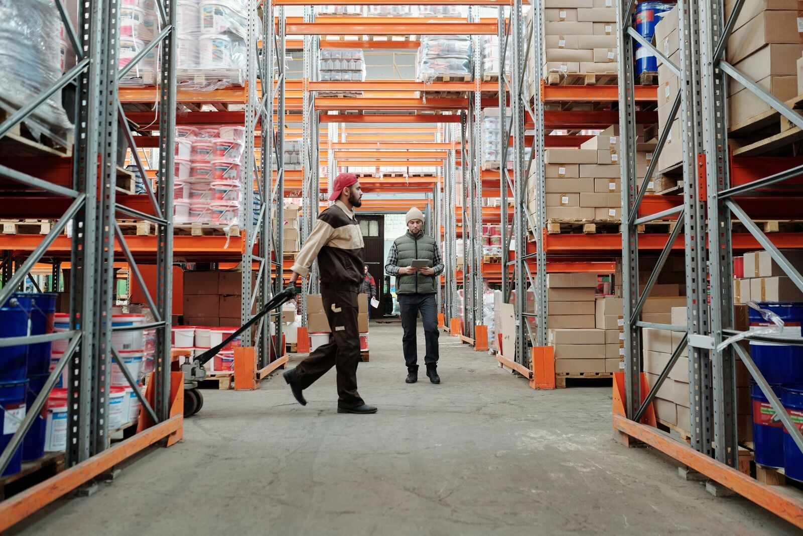 Dos empleados recorren un pasillo de almacén entre estantes de mercancía
