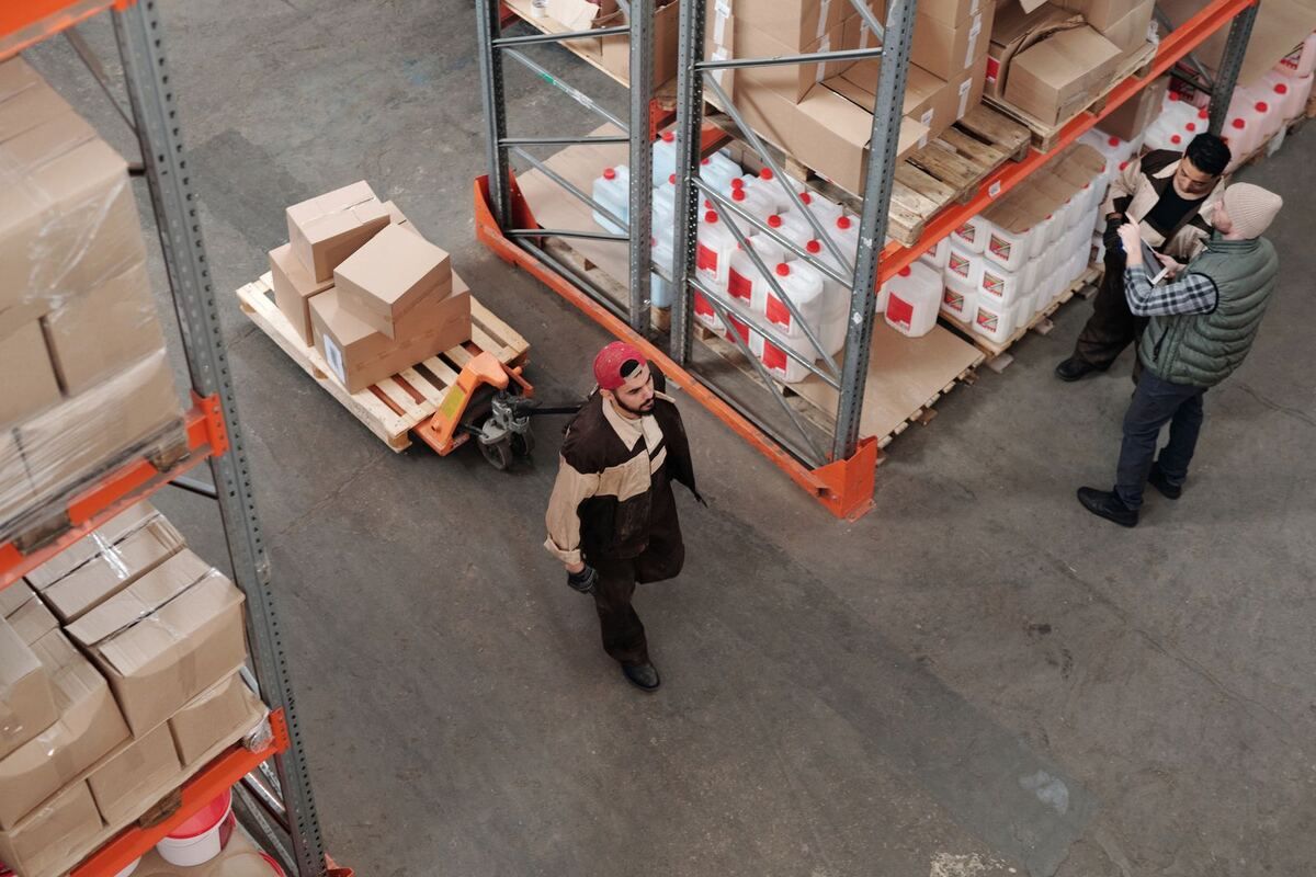 Vista cenital de trabajadores acomodando tarimas en un almacén